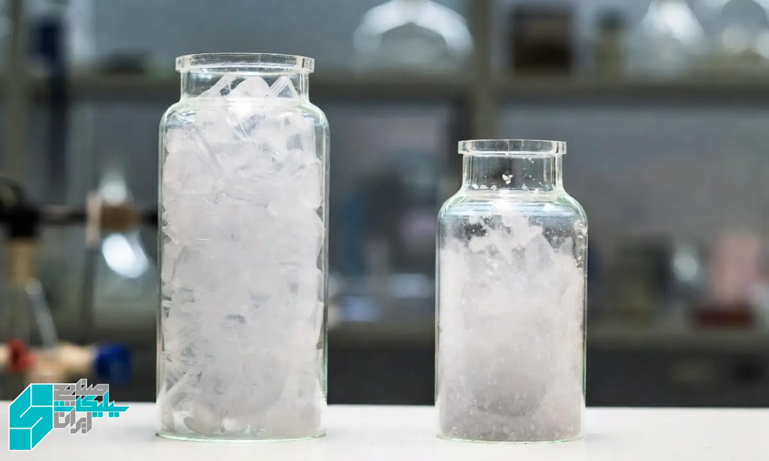 مقایسه دو نمونه دانه بندی سیلیکات سدیم جامد در دو ظرف شفاف، یکی با ذرات یکنواخت و دیگری با ذرات نامنظم، روی میز آزمایشگاه فرمولاسیون شوینده